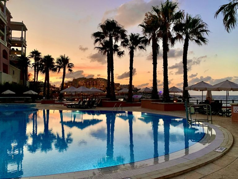 Resort pool and palm trees at sunset